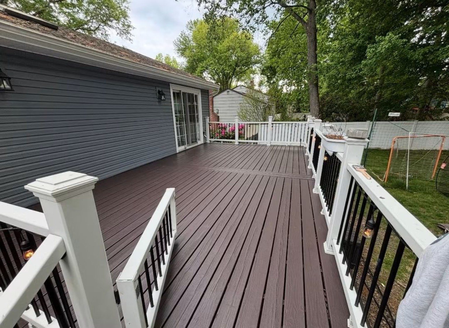 Finished dark deck surface with white railings viewed across the outdoor living area.