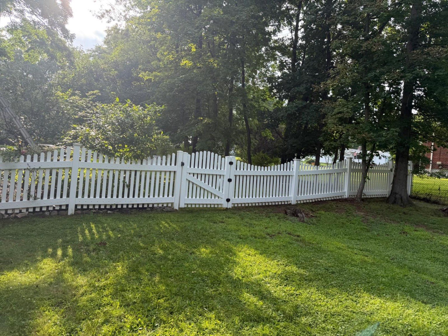 Wide view of the cleaned white fence extending across the landscaped yard.