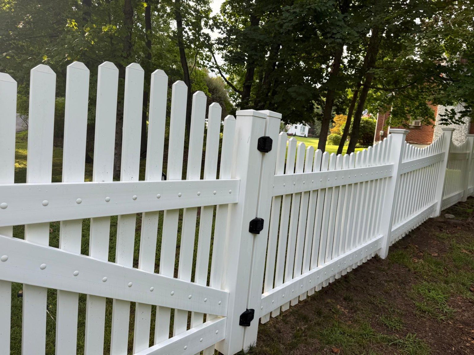 Close view of a cleaned white vinyl gate and fence with black hardware.