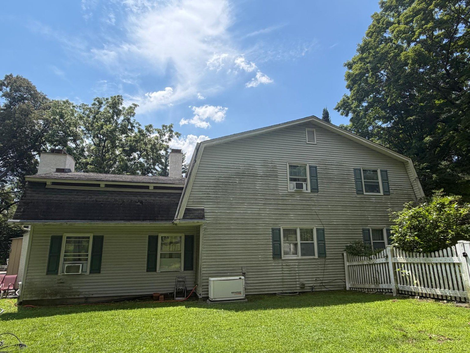 Rear exterior siding before cleaning with visible dark and green organic discoloration.