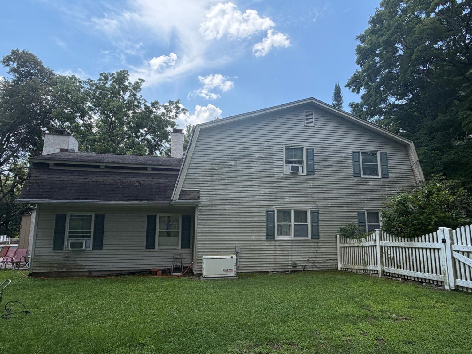 Wide rear view of the home before cleaning with visible discoloration across the siding.