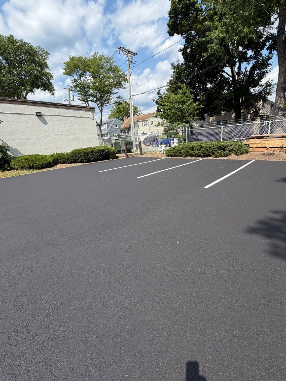 Finished parking spaces viewed toward the fenced edge of the commercial property.