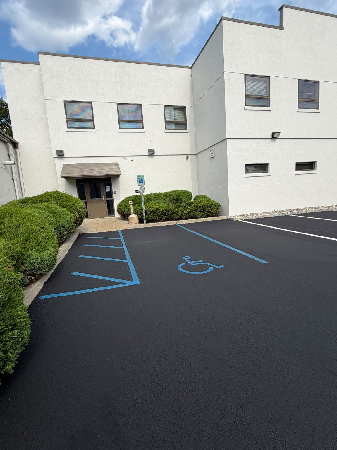 Finished commercial parking area with dark pavement and bright accessible parking markings.