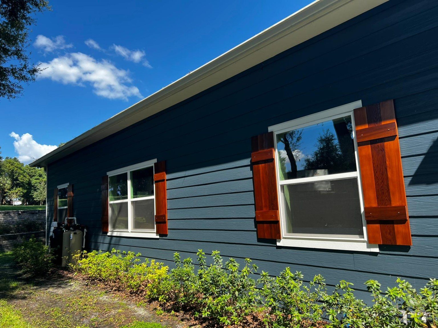 Dark-blue home exterior with white window trim and warm-toned cedar shutters.